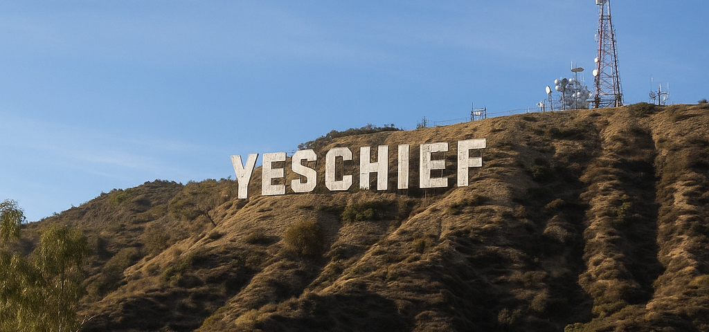 Hillside with a large 'YESCHIEF' sign against a blue sky.